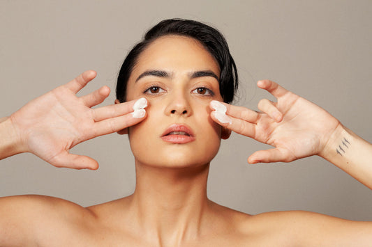 27 year old white model with Skin Virtue cream of her fingers holding them close to both sides of her face