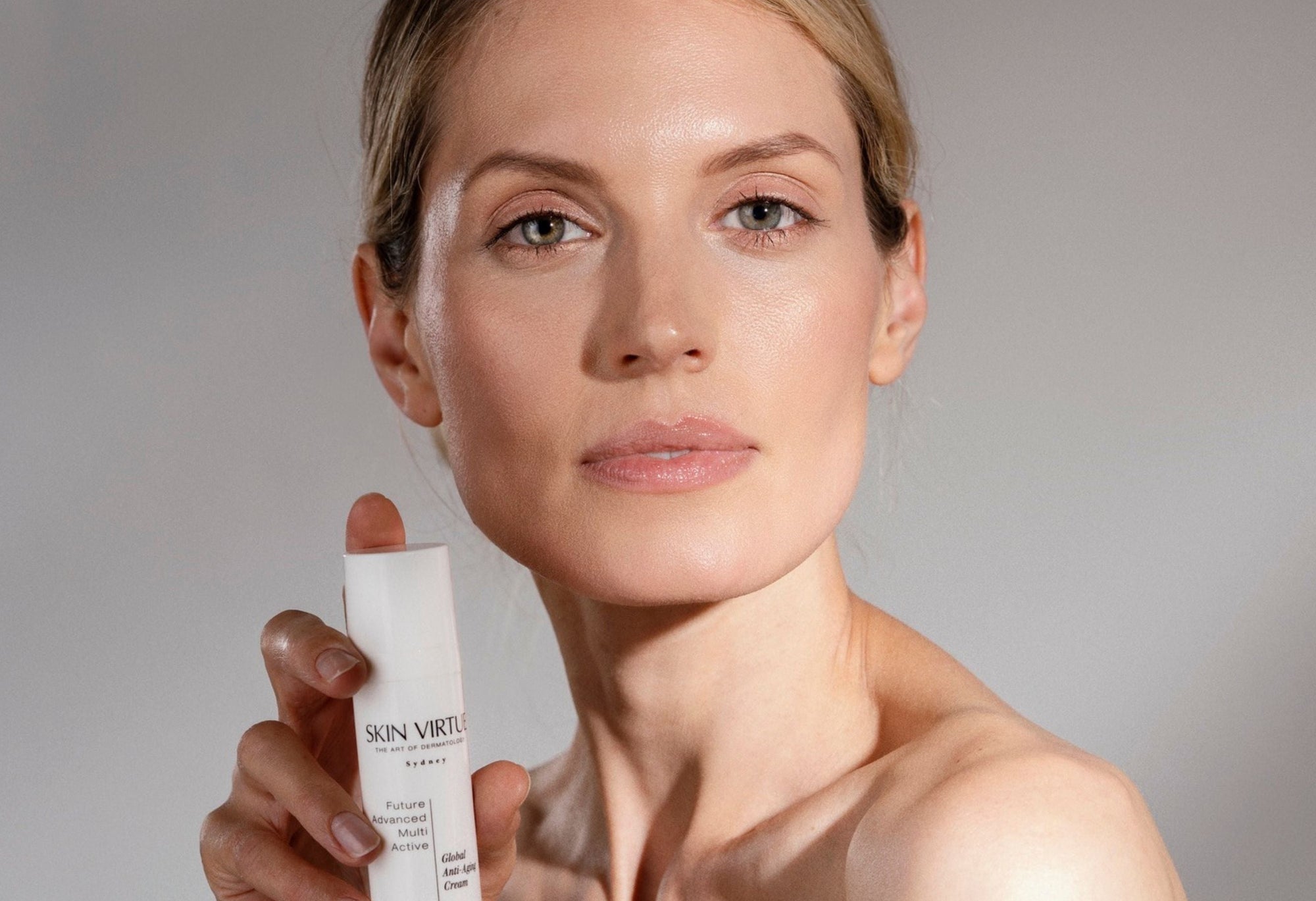 Female model holding a Skin Virtue  skincare product with a neutral background